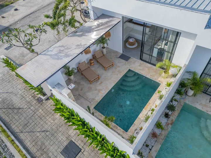 Aerial view of a square courtyard pool surrounded by white walls and planting.