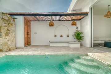 Courtyard pool with stepped entry facing a stone terrace, arched wall niche and timber pergola.