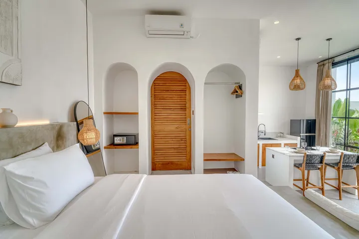 View from the bed toward an arched timber door, the kitchen counter and arched niches.