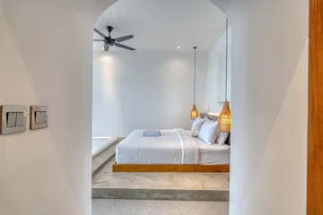Low bed framed by an arched doorway, with a ceiling fan and pale walls.