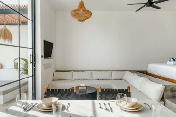 View across the living area toward the courtyard, with bed edge, sectional and television visible.