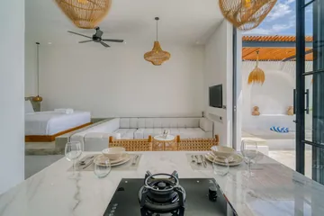 Kitchen island and dining setting beneath woven pendants beside glass doors.