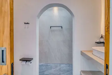 Walk-in shower with pale stone walls and a recessed shower head.