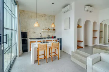 Dining table and kitchen beside floor-to-ceiling glass, with built-in arched wall niches.