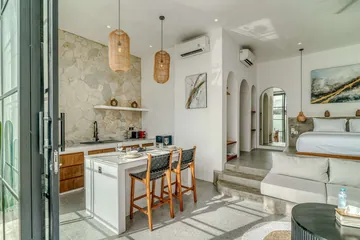 Stone-backed kitchen and dining island, with the bed and artwork beyond.