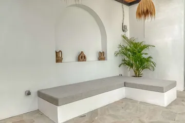 Built-in stone bench beneath an arched wall niche, with small decorative objects on the ledge.