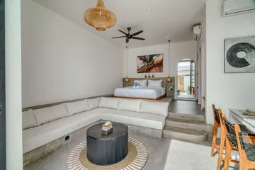 Open-plan room with bed and sectional seating, looking toward glass doors and the courtyard.