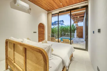 Bed with a woven rattan headboard beside glass doors to the courtyard pool.