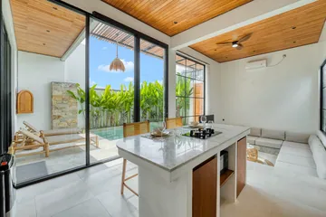 Kitchen island and cooking area framed by glass walls and timber ceiling panels.