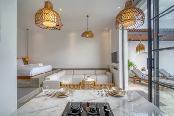 Kitchen island set for two beside the sectional sofa and a low bed visible through glass.