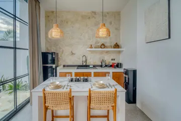 Dining table set with place settings in front of a stone-backed kitchen and glass doors.