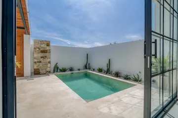 Small pool courtyard viewed through glass doors beside pale paving.