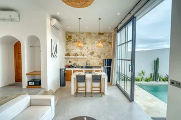 Dining table and kitchen beside glass doors overlooking the courtyard pool.