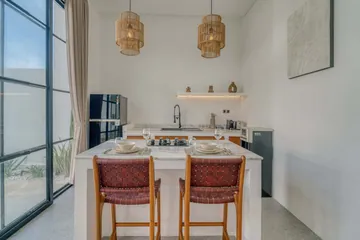 Two dining stools at a kitchen counter beside a tall black refrigerator.