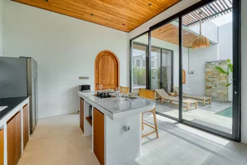 Kitchen and lounge with island counter, glass doors and timber ceiling.