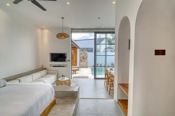 View from the bed through the living area toward glass doors opening onto the courtyard.