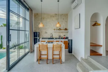 Dining table and kitchen beside black-framed glass doors, with built-in arched shelves.