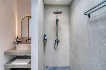 Stone shower and vanity viewed through an arched doorway.