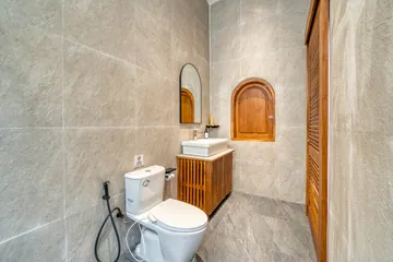 Bathroom vanity and shower with pale stone walls and wood accents.