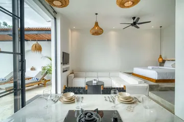 Dining table and kitchen island beside a glass wall, with the courtyard visible outside.