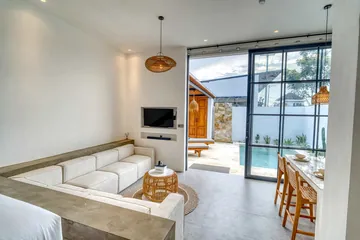 Sectional sofa facing a wall-mounted television beside glass doors and a small dining table.