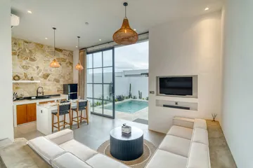 Sectional seating, wall-mounted television and dining counter in a bright room opening to the courtyard.