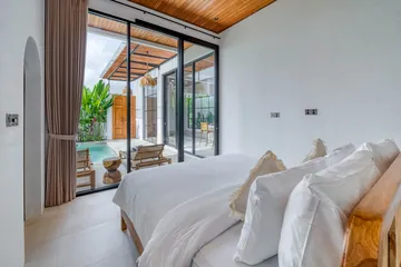 Bedroom with a white bed beside glass doors opening to the courtyard.