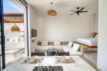 Dining table set for two in front of the sectional sofa and bed, with glass doors open to the courtyard.