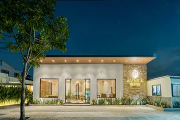 The AVASA lobby at night with broad windows, planting and a stone wall bearing the AVASA sign.