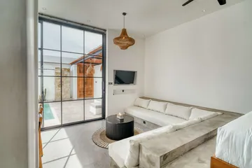 Sectional sofa, round coffee table and wall-mounted television beside tall glass doors to the courtyard.