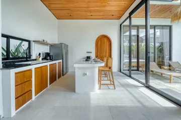 A long kitchen with timber cabinetry and an island facing the glazed courtyard.