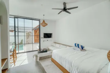 View across the bed and sectional toward glass doors opening onto the courtyard.