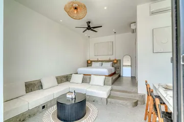 Sectional sofa and round coffee table in front of a low bed, beside an open glass door.