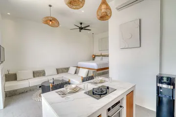 Kitchen island with cooktop and place settings in front of the sectional sofa and bed.