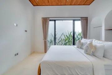 White bed facing a curtained glass door in a bright room.