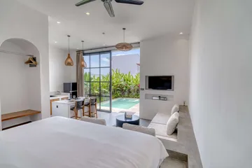 View from the bed across a sectional sofa toward glass doors opening onto the courtyard.