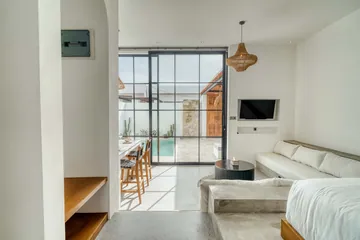 Living room with pale sectional and wall-mounted television facing an open glass doorway.