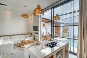 Kitchen island with place settings and a sectional sofa beyond, beside tall black-framed glazing.
