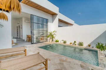 Poolside terrace with pale paving and a white villa facade.