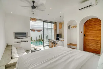 View from the bed toward a wall-mounted television, glass doors and an arched timber door.