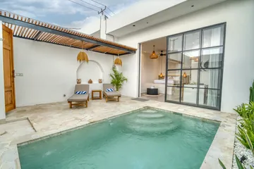 Rectangular courtyard pool in front of sliding glass doors, with loungers and stone paving.