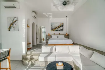 Low bed and sectional sofa beneath a ceiling fan, with arched niches along the wall.