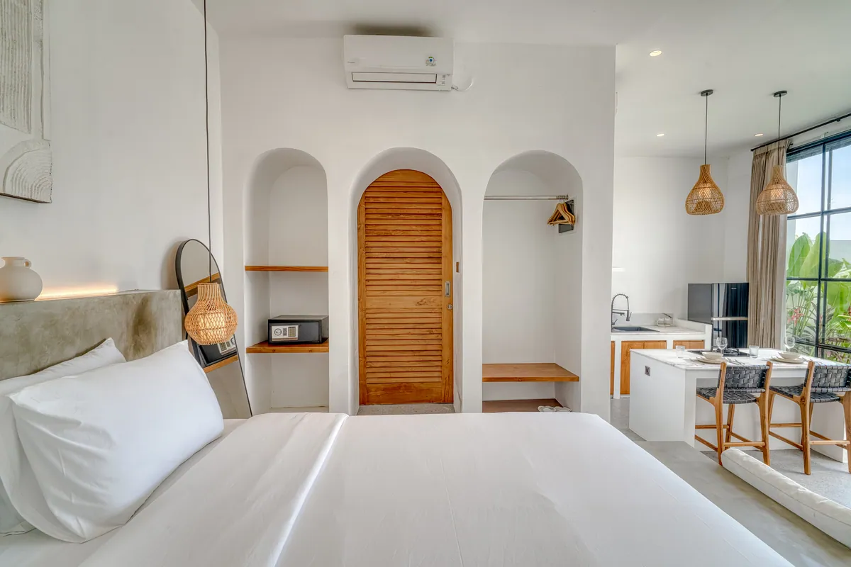 View from the bed toward an arched timber door, the kitchen counter and arched niches.